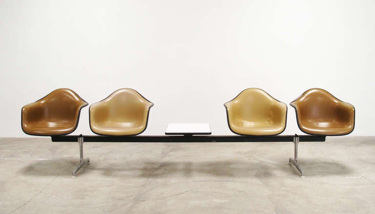 The longest version of the tandem seating bench unit designed by Charles & Ray Eames and made by Herman Miller, 1960s. A cast aluminum base and lacquered steel crossbar support four fiberglass armchairs upholstered in original tan and brown