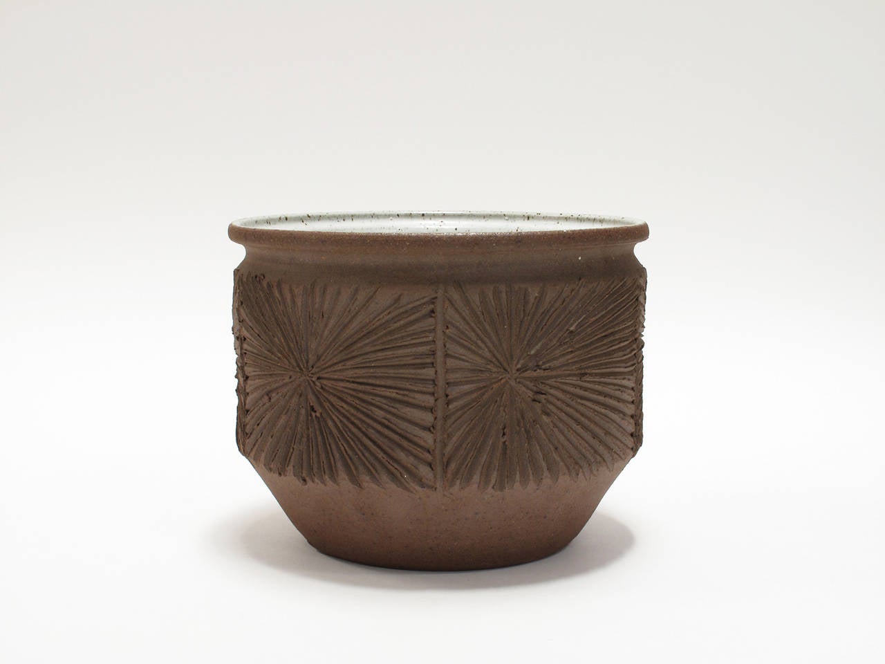 Stoneware vessel featuring an unglazed, hand-incised exterior with the 
