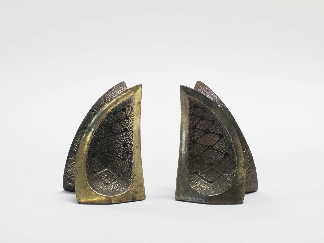 Pair of enigmatic Mid-Century Modern bookends in brass-plated cast metal, featuring an incised motif of something cosmic, in the style of Ben Seibel and Jenfred Ware, 1950s.