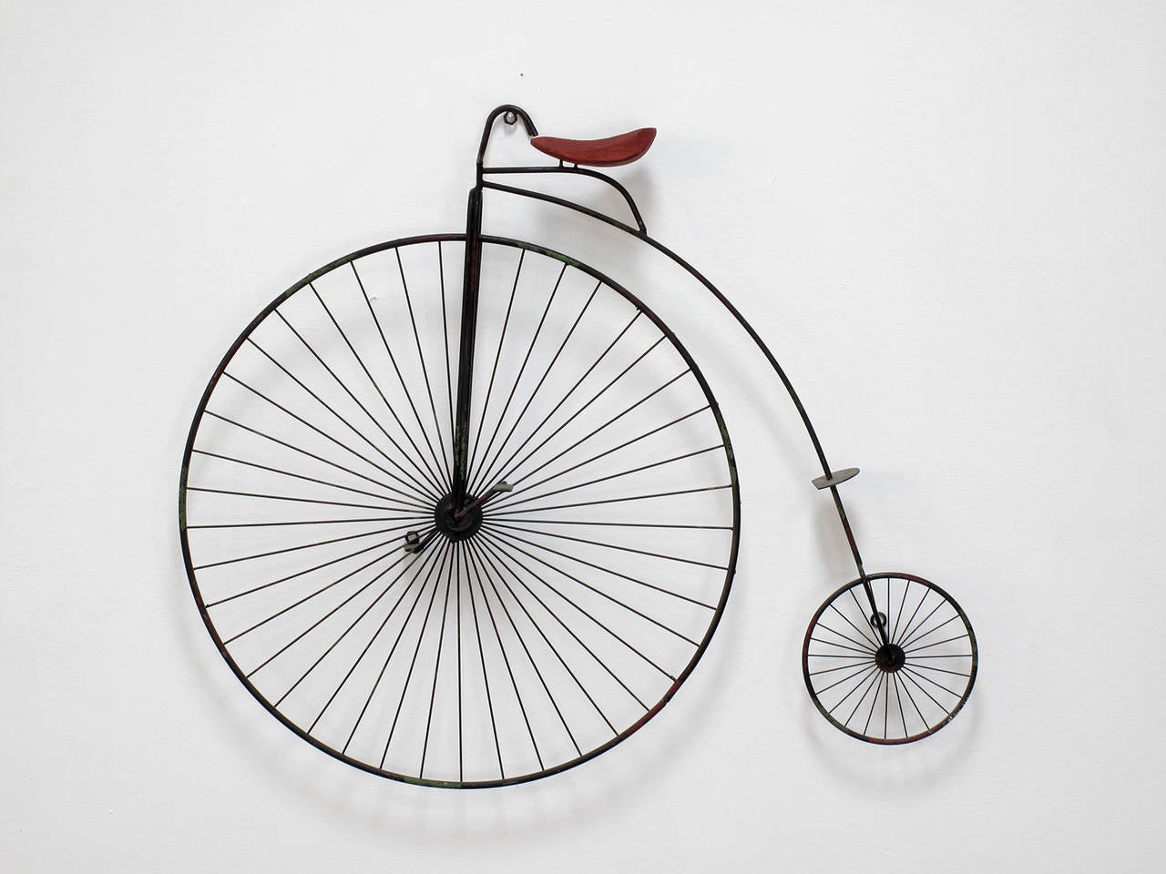 Wall-mounted sculpture in the shape of a high wheel bicycle in hand fashioned metal, paint and wood designed and made by Curtis Jere, signed and dated.