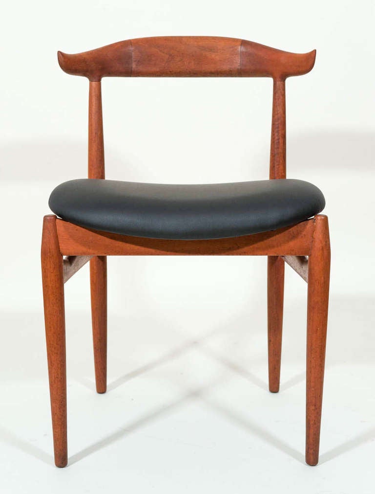 A set of four stylish teak dinning chairs in the style of 
Hans Wegner. The chairs have been cleaned, oiled and reupholstered with faux black leather.