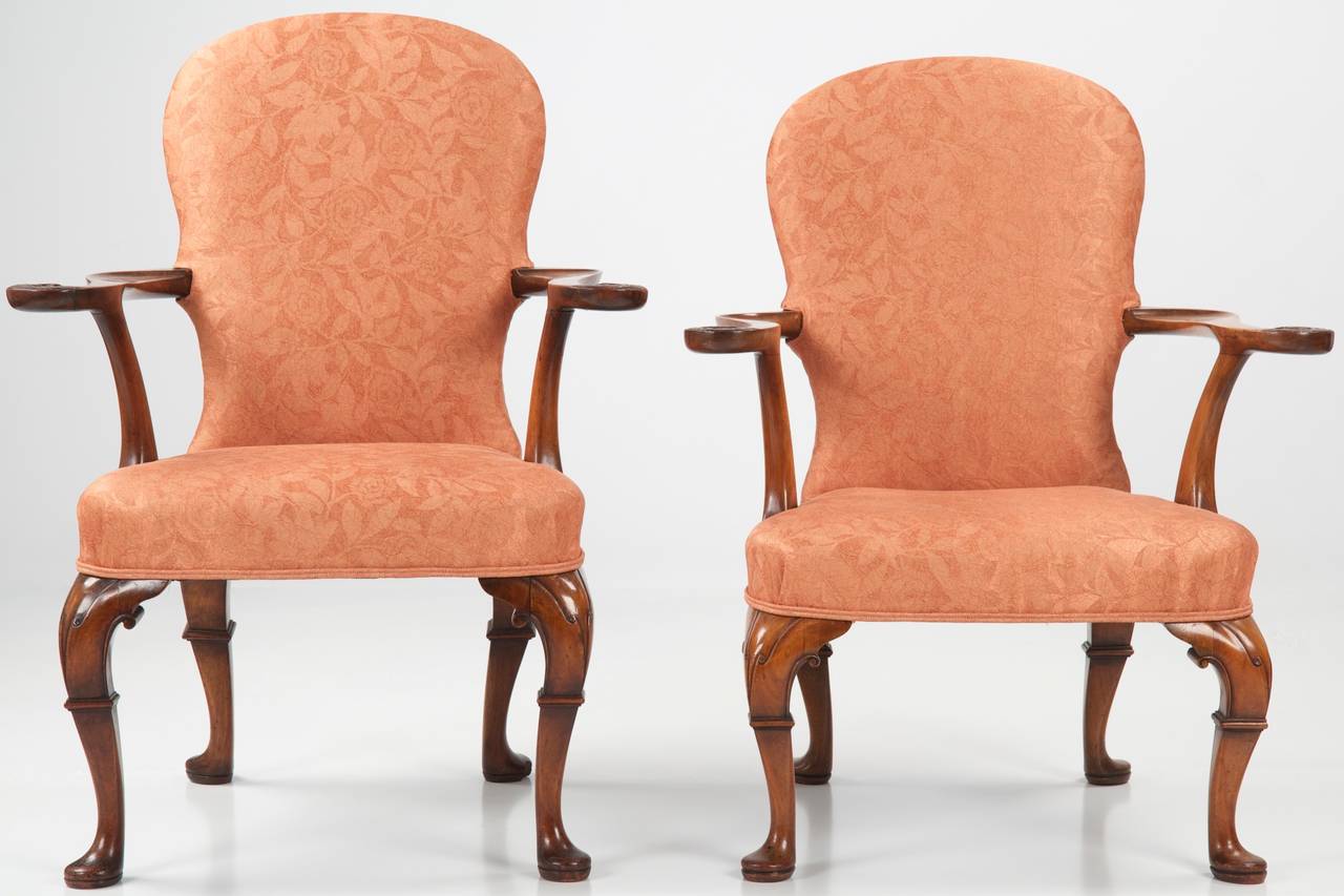 This absolutely gorgeous pair of George II style walnut open arm chairs were probably crafted during the last years of the nineteenth century, possibly as late as 1910.  The surfaces positively glow with a deep well worn patina beneath many layers
