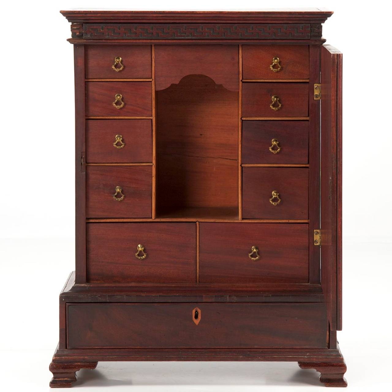 Crafted of wonderfully vibrant mahogany primary woods, this fine English spice cabinet is quite expressive with an unusual sense of presence. The finished top is edged by projecting molding over original and untouched pierced Greek-key fretwork. The