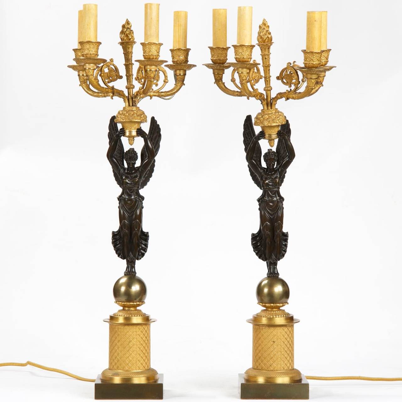 A very fine pair of French Empire Style Gilt and Patinated Bronze Four-Light Candelabra raised over the allegorical 