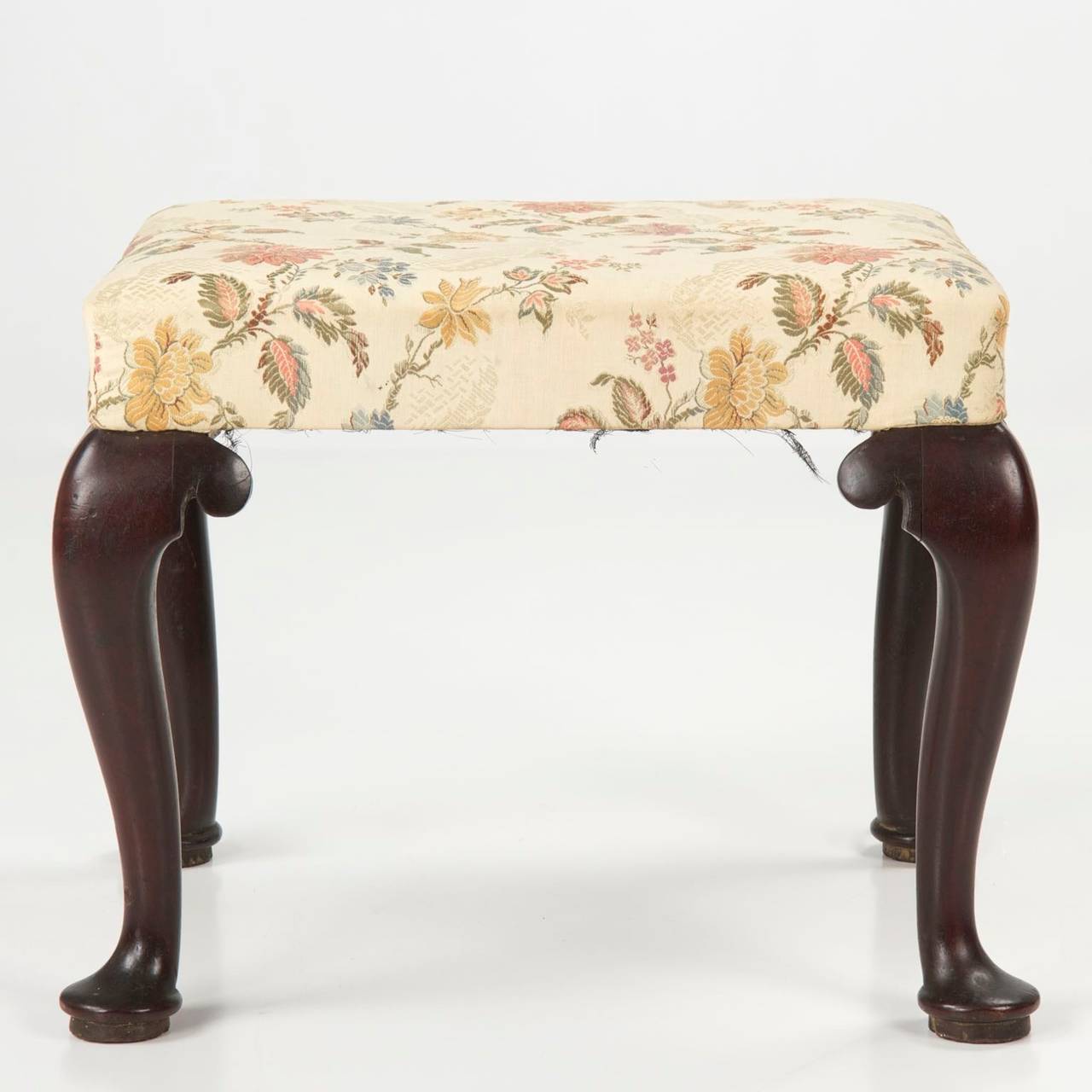 A precious and rare find, this fine English George II period foot stool remains in positively pristine condition.  The early finish is oxidized, dry and full of character along the handsomely carved cabriole legs with plain scrolled returns.  The