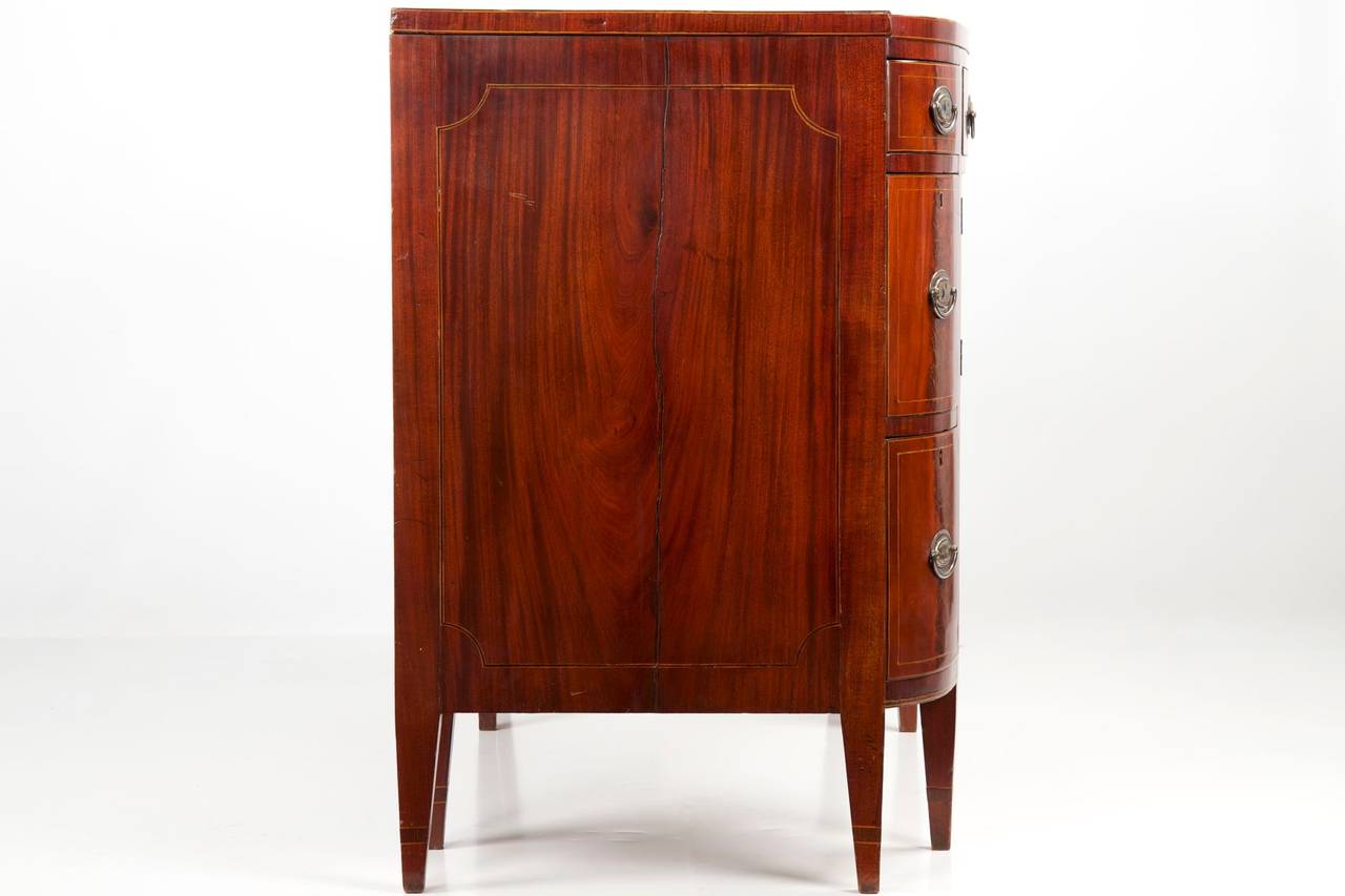 Large and of a particularly striking form, this bold and uncommon sideboard is noteworthy for it's bowed curvature and unusual height.  Three smaller graduated drawers flank a single broad drawer over a pair of doors, these opening to reveal a large