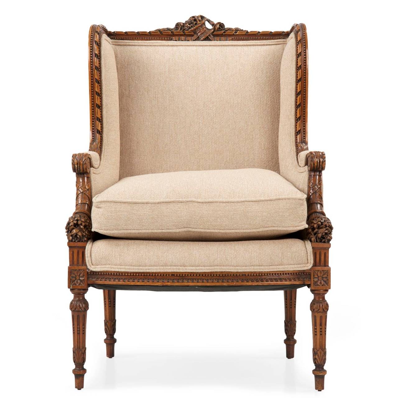 Exquisitely carved, this fine Louis XVI Style wingback arm chair was crafted during the Rococo Revival period.  The crest rail is highlighted by a very complex carving of a woven basket with flowers spilling out from it, ribbons flowing from around