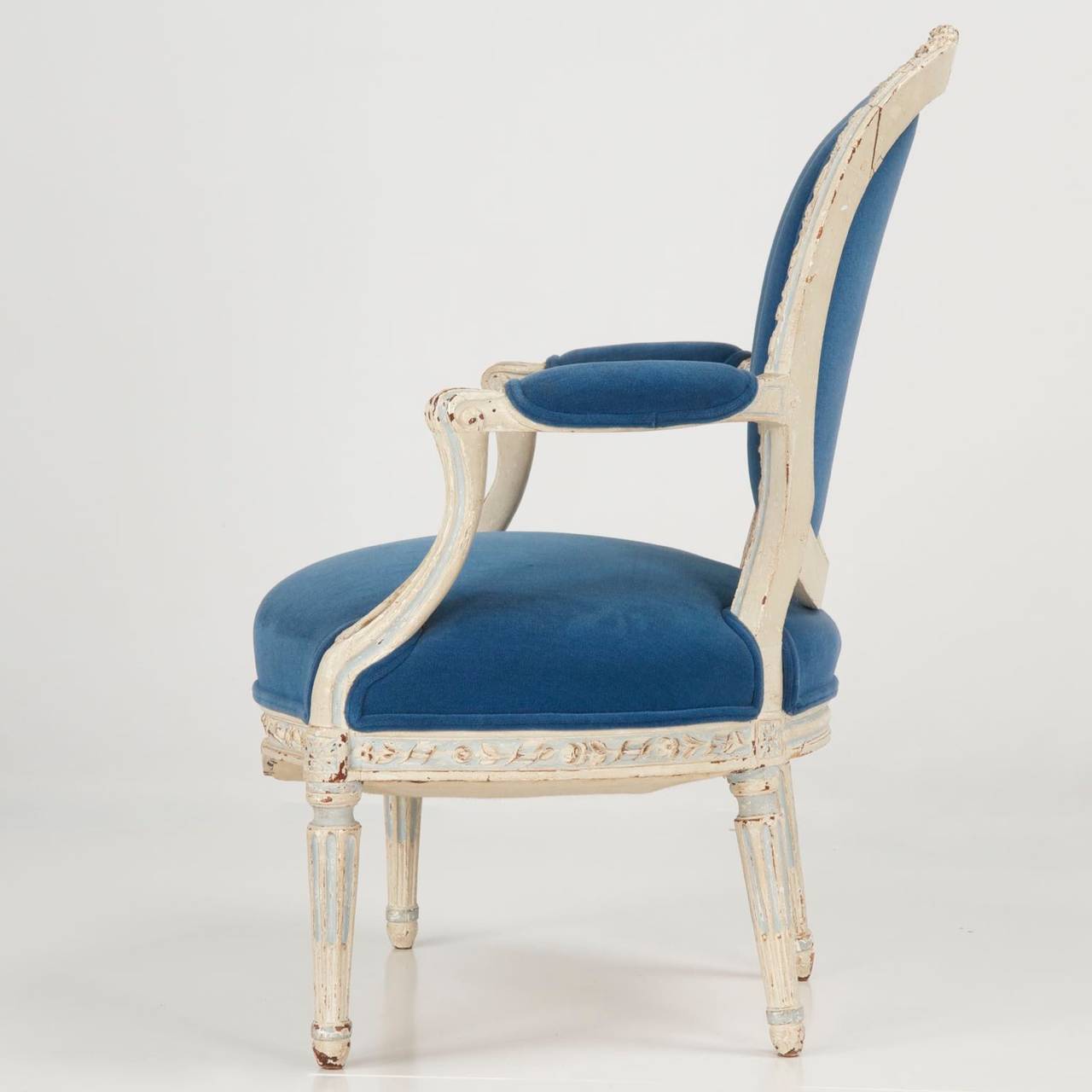 Exquisitely carved and detailed, this fine French open-arm fauteuil was clearly crafted by a fluent and creative hand.  The crest rail culminates from the rather varied rail molding in a robust display of flowers carved from the solid rail.  Each