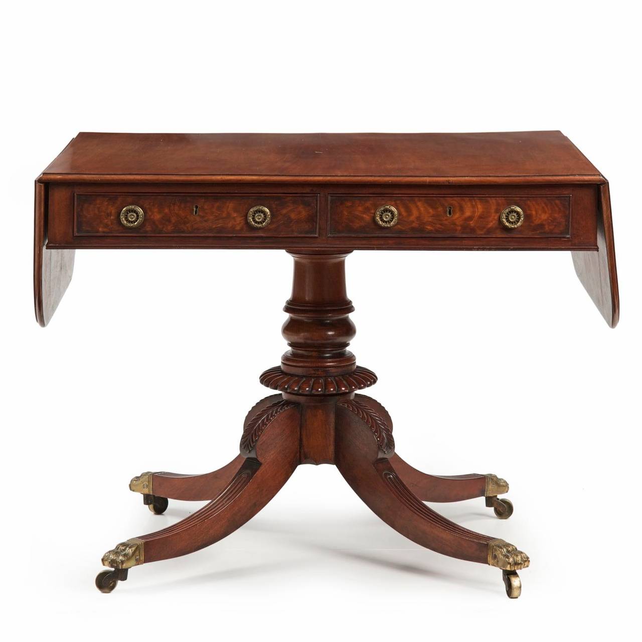 A finely crafted table of the Regency period, this sofa table features a vibrant solid mahogany top with molded edges of the solid, the outer leaves raising on original iron hinges over two knuckled wings to create a wide presentation space.  The