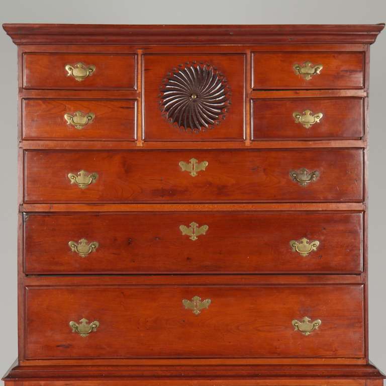 With a molded cornice projecting boldly over the pair of stacked drawers on either side flanking a square drawer with a spinning pinwheel decoration, the case exudes presence while exhibiting wonderful proportions at only 71 1/8