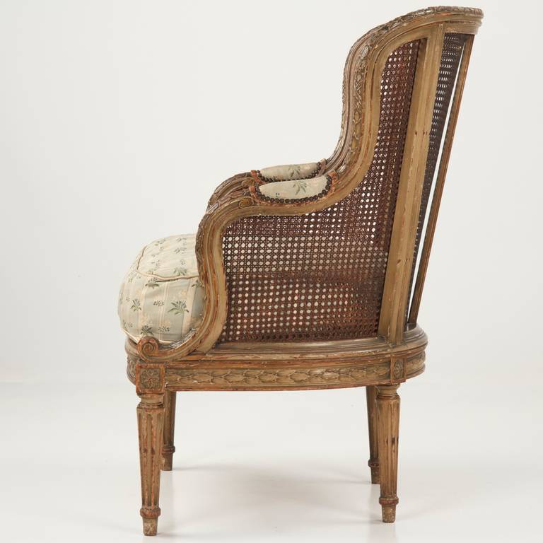 FINELY CARVED FRENCH LOUIS XVI BERGERE ARM CHAIR
France, c. 1890

With a truly magnificent level of carved detail, this antique French armchair makes quite a statement. The entire crest rail and frame is embellished with variated motifs of