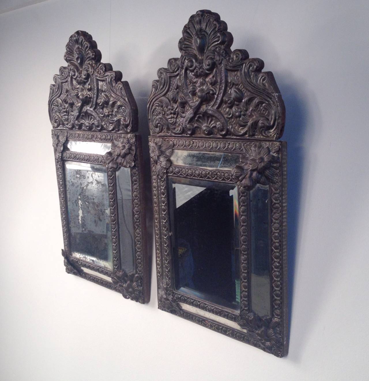 A pair of Baroque brass repoussé mirrors from Belgium. The front is in five sections of mirror, surrounded by pounded brass relief, with a wood back. 
Belgium, circa 1850.