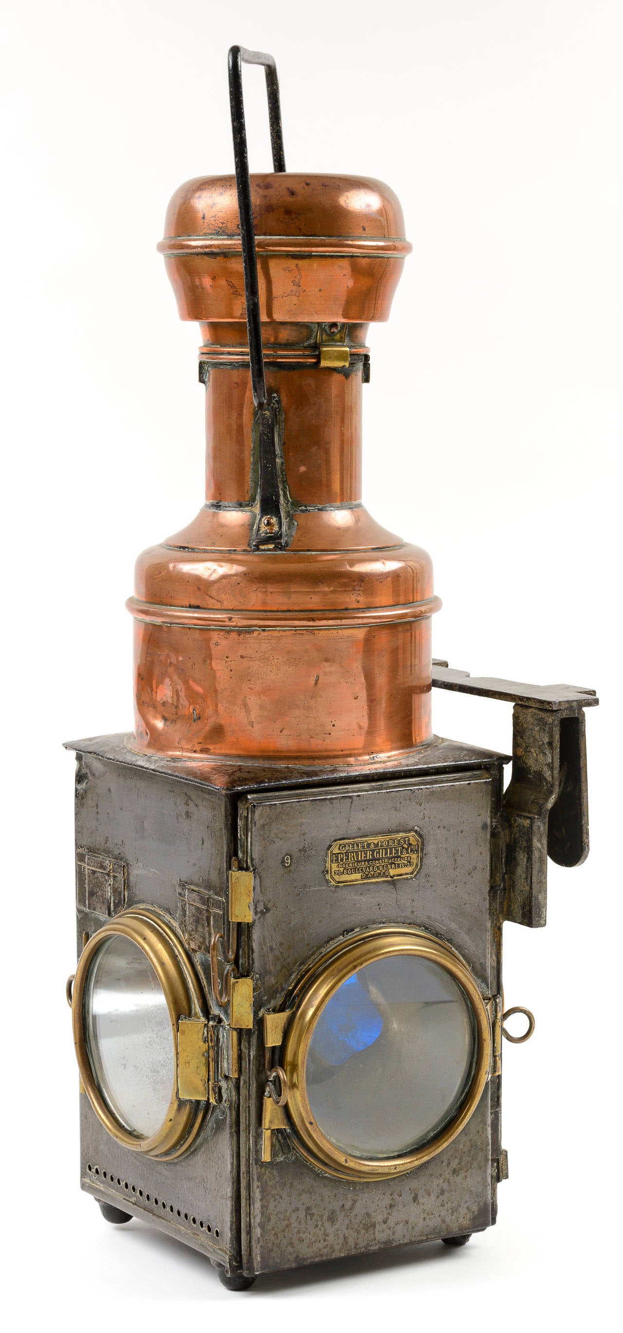 Handsome railroad lantern with tooled brass and copper detail. The piece has three round windows with brass fittings.  The tall copper chimney has a handle for carrying.  The chimney top is hinged.  It has a forged bracket for hanging.
