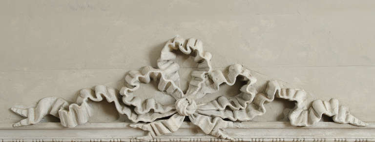 Questo grande trumeau del XVIII secolo ha un pannello bianco rialzato con angoli dentellati, ciascuno con una piccola rosetta. Un profondo arco in rilievo si trova nella parte inferiore del pannello. Il 
La vernice è grigia. Il vetro viene