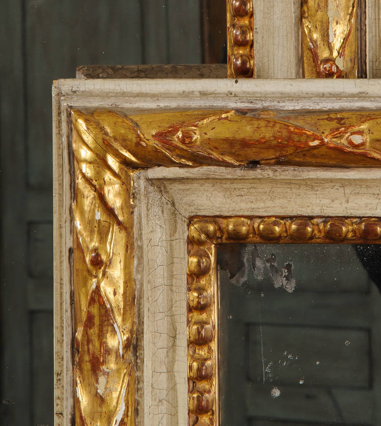The matched pair of Louis XVI style mirrors have a boldly carved molding of acanthus leaves with a middle convex panel. The inner molding has dot and dash detail with an additional palmetto detailed molding on the fourth side. The water gilded gesso