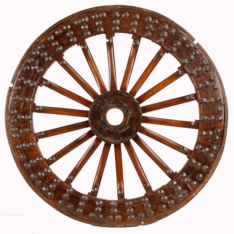 A massive Chinese cart wheel with iron tread and large nailhead detail.
The spokes are tapered and splayed.