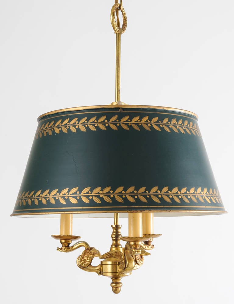 The proportion and scale of the bouitllette lamp are indicative of its fine workmanship. The arms of the lamp are three finely cast swans in bronze. The candle cups have tiny bead detail. The tole shade is original and is in excellent condition.