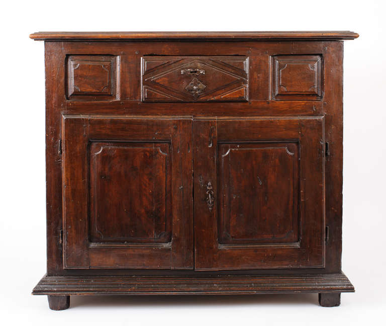 The Louis XIII buffet has deeply carved geometric panels on the front and sides of the base cabinet, drawer and doors. The raised panels on the front have notched corners. This piece is from SW France. It shows a strong Spanish influence.