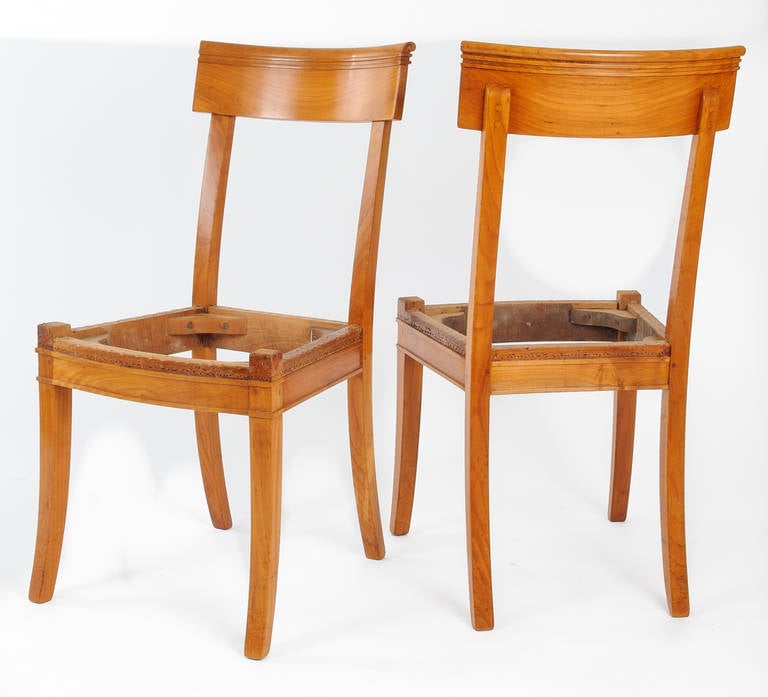 Set of six Directoire dining chairs in cherrywood. Curved chair back with delicate scroll detail and double raised band. The double band is repeated on the apron of the seat. The front and rear legs are scabbard shape.