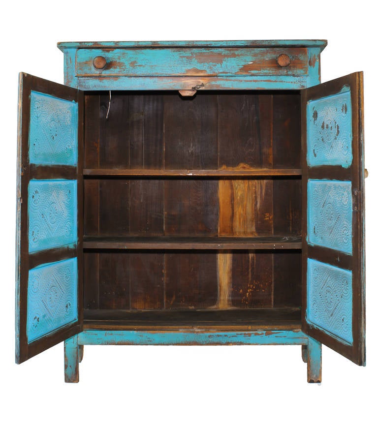 The color of the original paint on the cabinet and the punched tin makes this piece a standout in any room. The hardware is original.