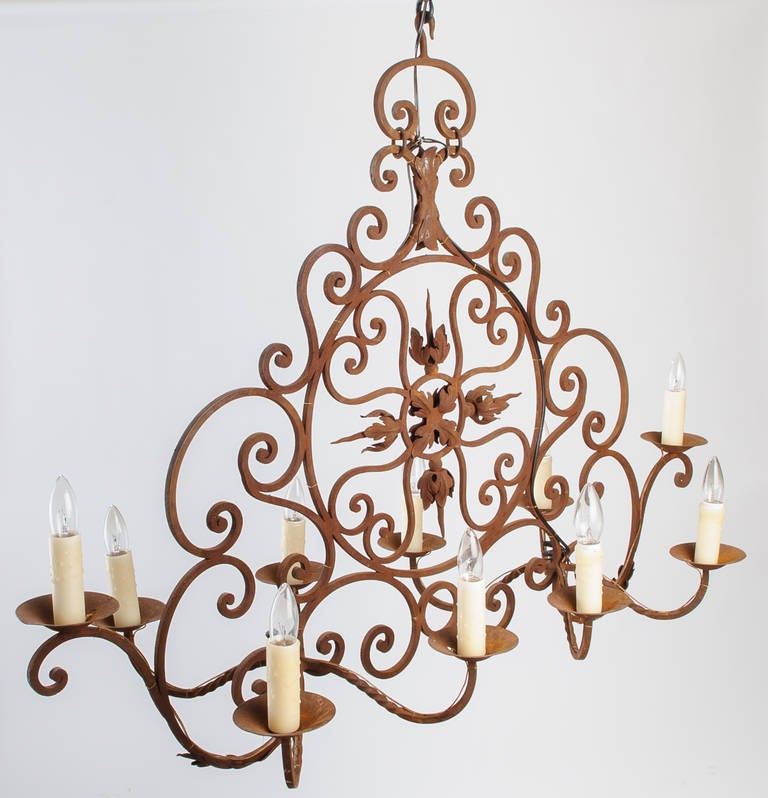 This elongated iron chandelier with ten lights is a perfect choice to hang over a rectangular table or kitchen workspace. The round centre incorporates hearts and acanthus leaf shapes. The large scrolls add to the interest of this chandelier.