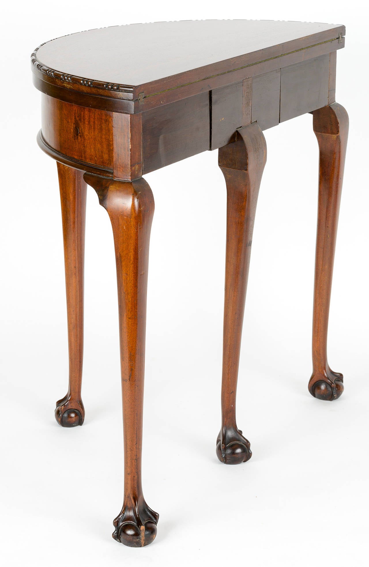 Mahogany George III demilune game table. The face top has bead detail edge.
The elongated cabriolet legs end in a nicely articulated ball and webbed foot. The fourth leg extends to support the open top and to expose a secret drawer. The brass hinge
