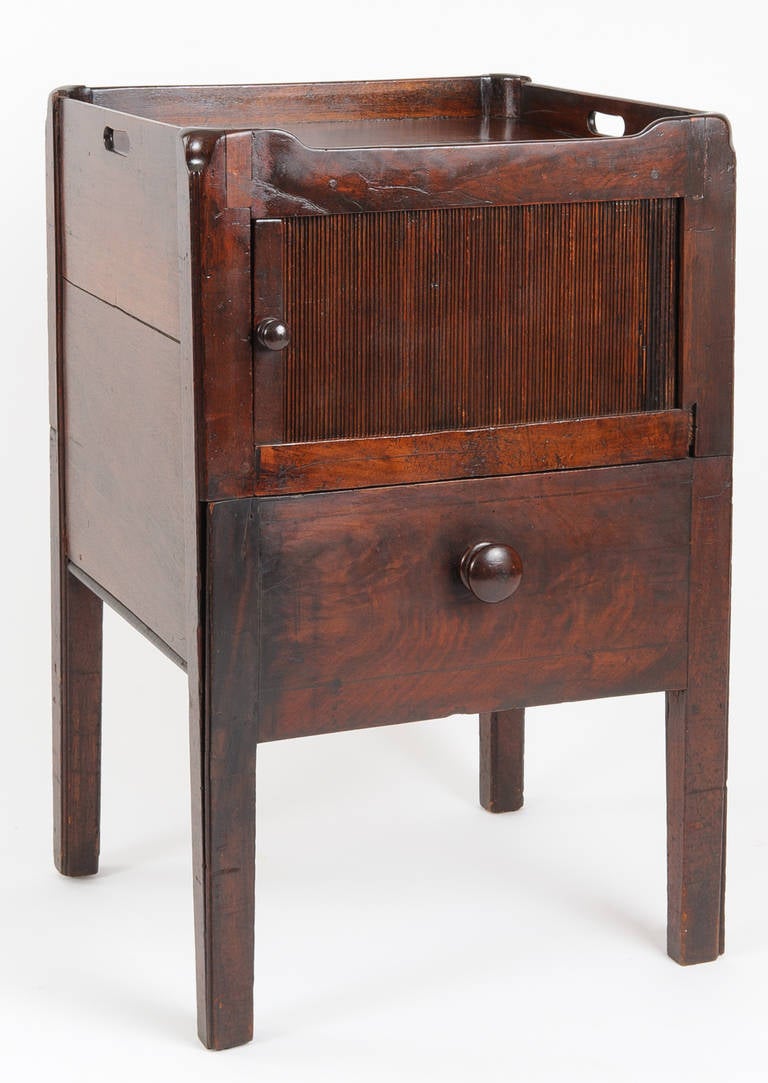Tray top night commode with tambour door and drawer. The mahogany wood is highly figured.