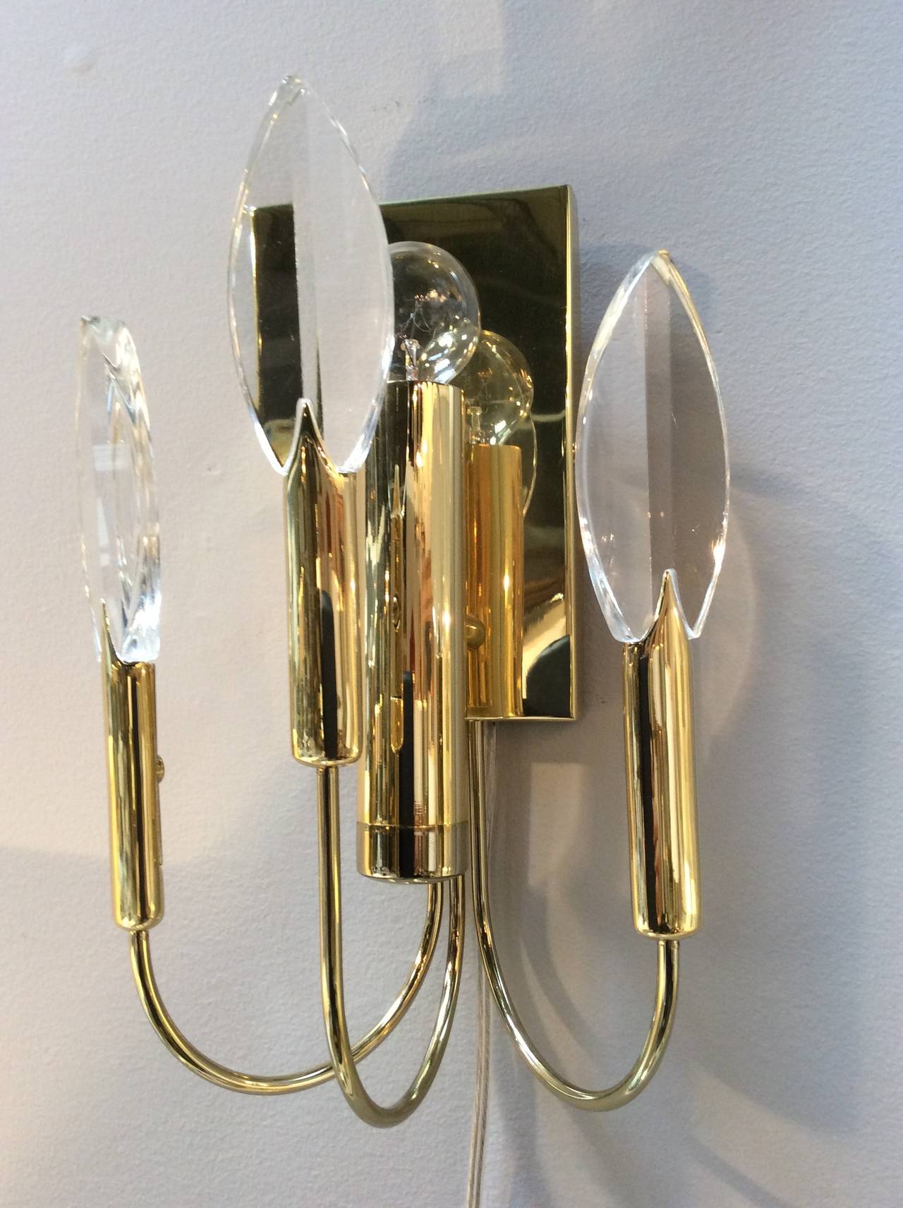 Three elegant crystal flames sit on curved brass arms and are backlit by a single bulb to capture the reflected light. All brass parts are newly plated and are left on lacquered to patina over time. Sconces attributed to Sciolari.