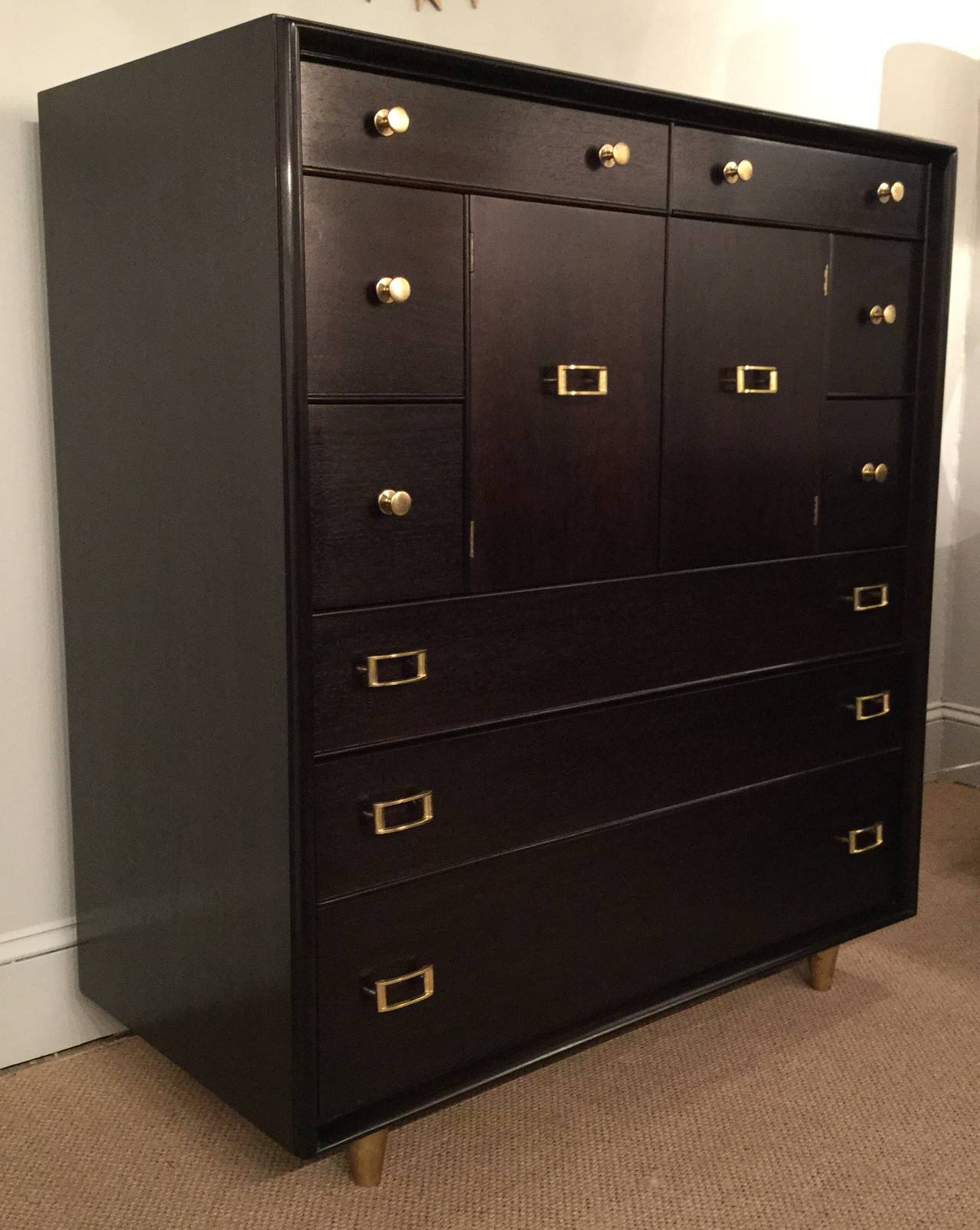 Newly ebonized walnut, tall chest of drawers with solid brass hardware by Paul Frankl.
A wonderful combination of nine deep and wide drawers, plus three concealed behind doors. Hardware, of solid brass is artfully manufactured and newly polished.