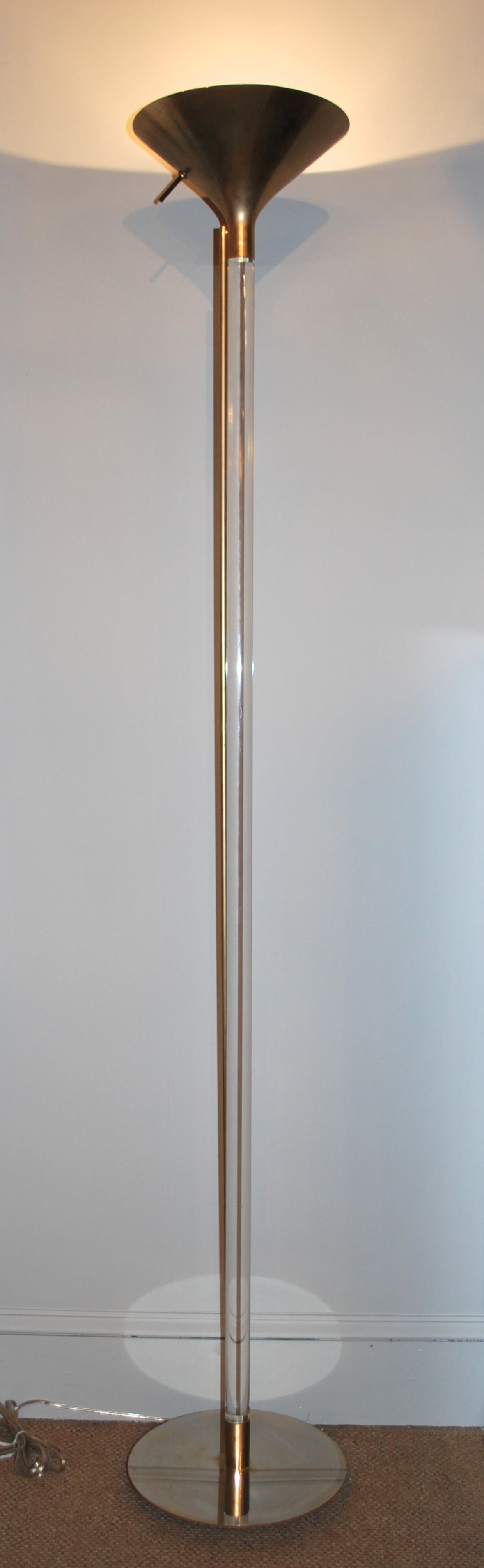 Supper tall floor lamp composed of a thick Lucite pole ending in cone shaped, matte brass shade, standing on a round brass base. Newly rewired.
Excellent condition.