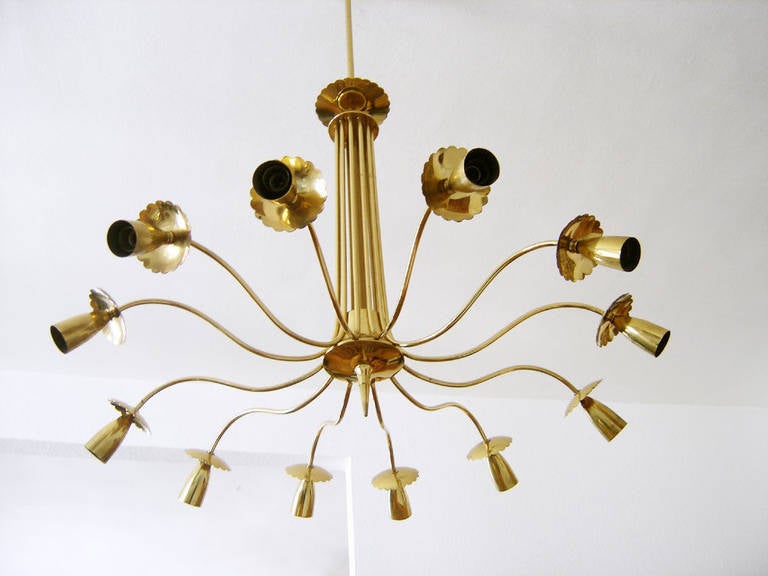 Elegant large-scale European brass chandelier, in the manner of Stillovo or Guglielmo Ulrich, with 12 undulating sculptural arms leading to beautifully crafted rosette adorned sockets. Stem and finial repeat rosette detail. Original canopy