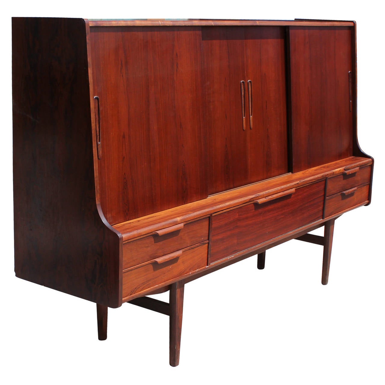 Tall rosewood credenza with sliding doors. Sliding doors on left and right open to reveal adjustable shelves. Center portion opens up to a dry bar complete with etched mirror back and three felt lined service drawers. Four drawers below sliding