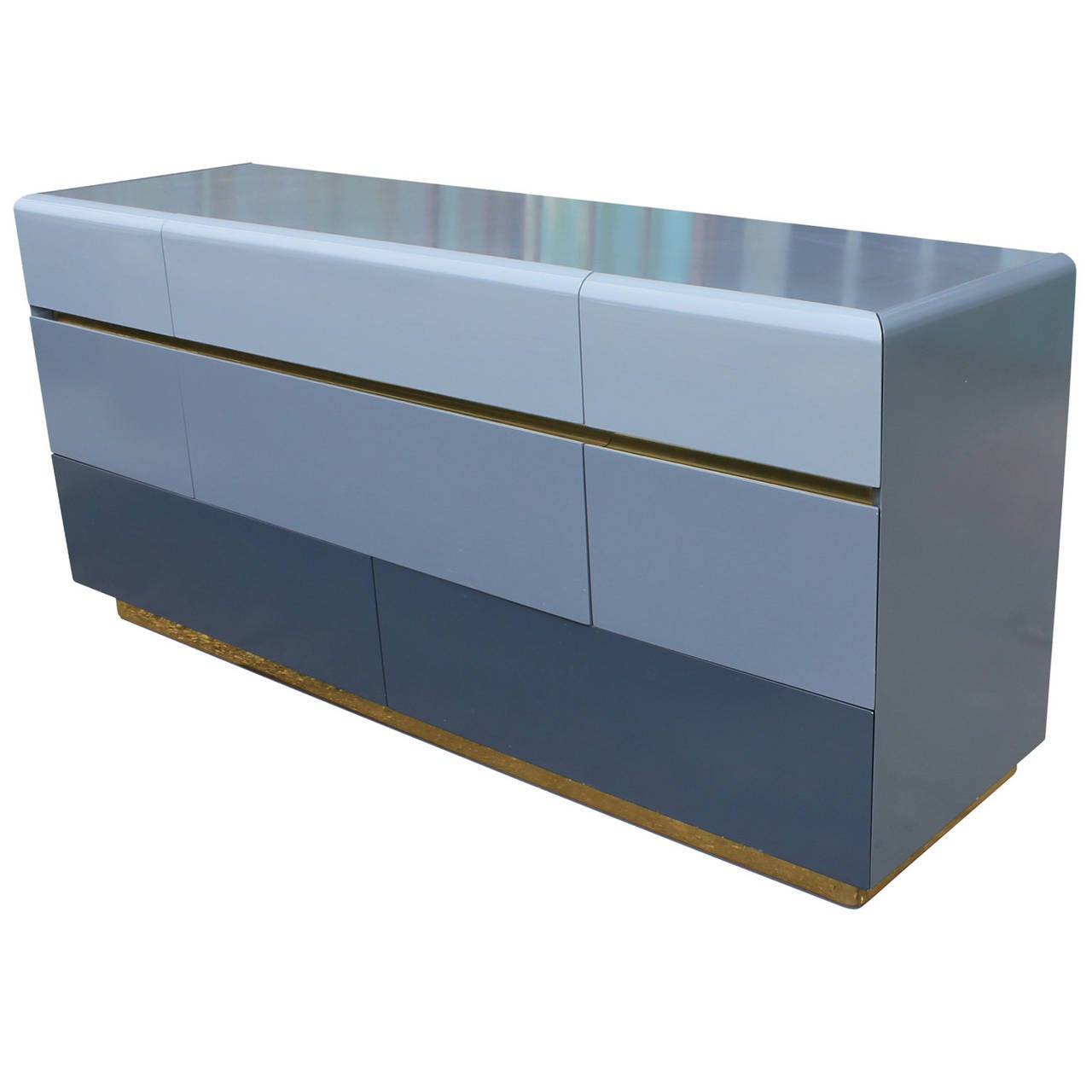 One of a kind dresser finished in an ombred high gloss lacquer. Base is wrapped in a shiny brass with another brass accent peeking out below the first drawer. Eight drawers provide ample storage.