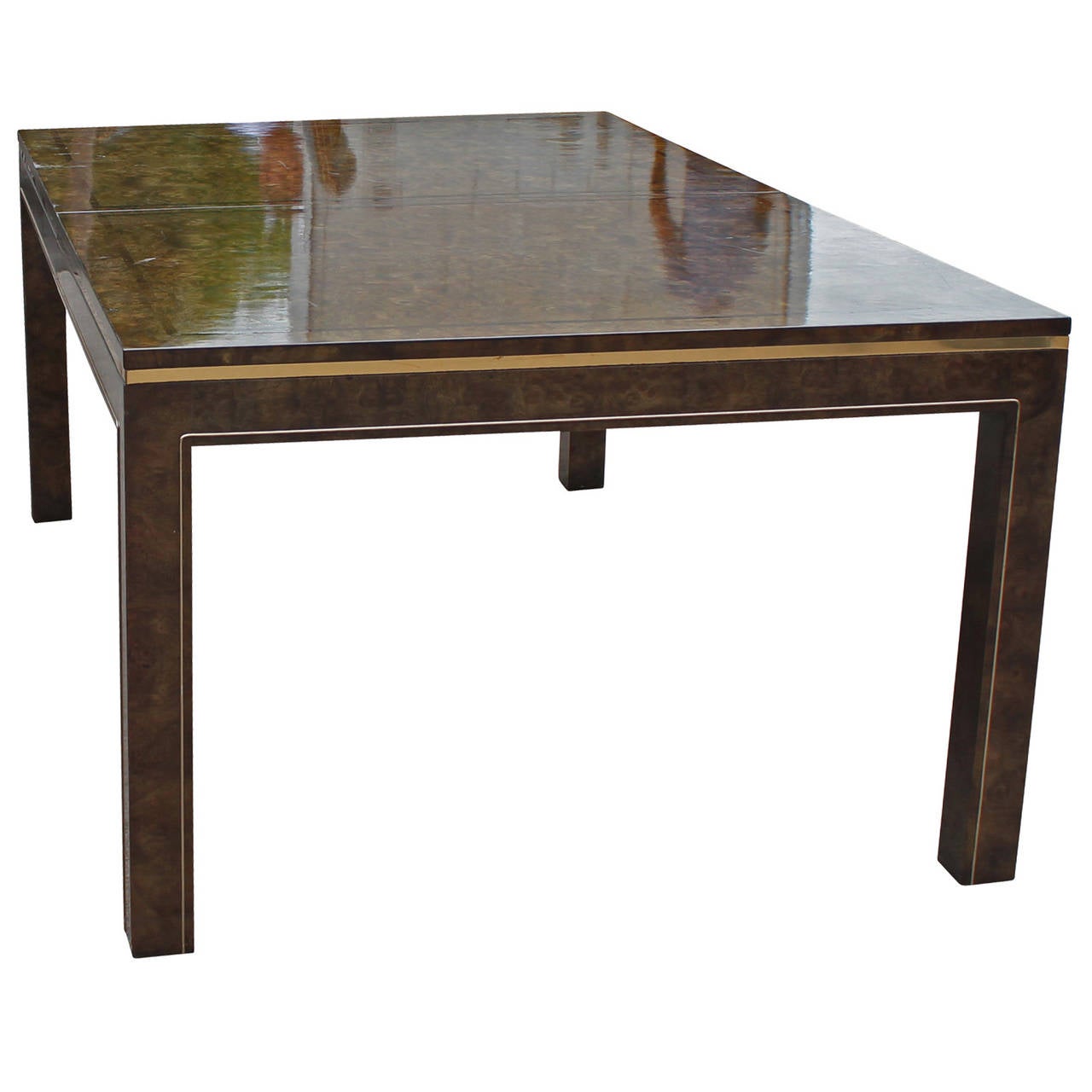 Mastercraft parsons style dining table in burl Amboyna wood with an inlaid rosewood border and brass accents. Table has a high gloss finish. A brass band wraps around the table top while another brass detail highlights the clean lined legs. Matching