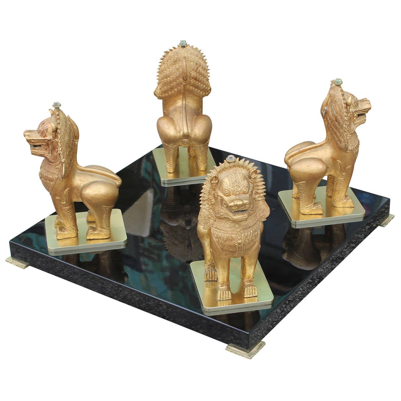 Stunning coffee or cocktail table. Four ornate Foo dogs sit atop a simple black Lacqured base with brass feet. A heavy beveled glass top rests upon the dogs' heads.