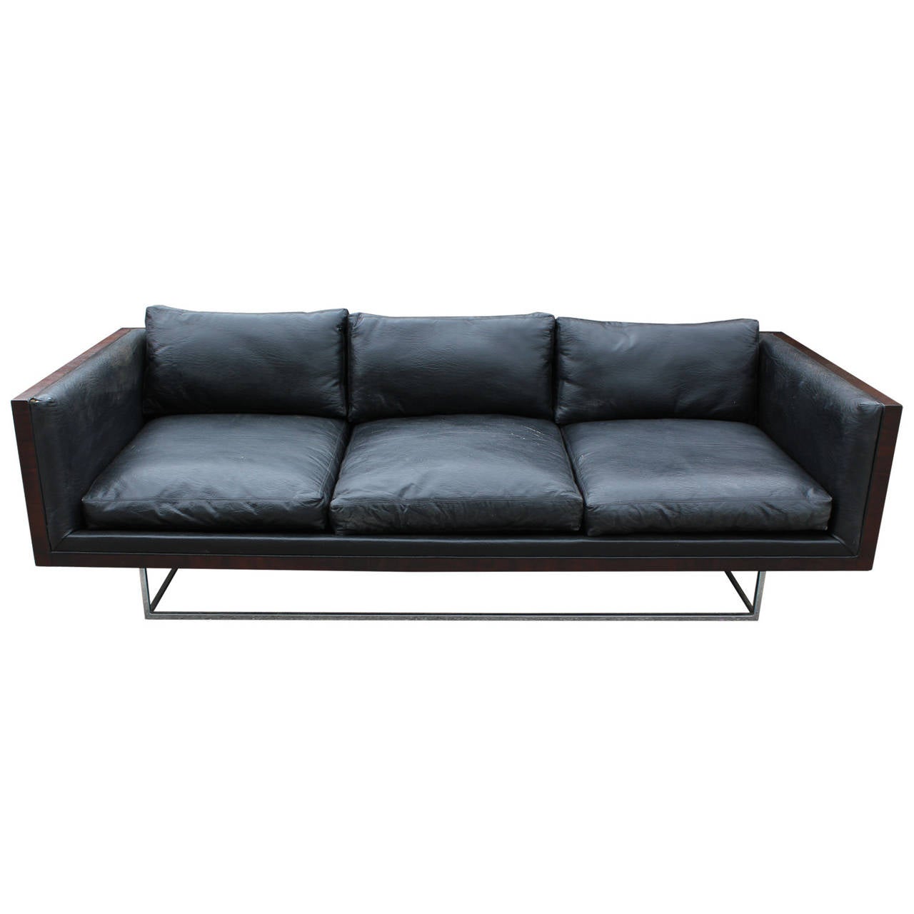 Sleek three-seat sofa by Milo Baughman for Thayer Coggin. Sofa has a stunning burl wood case and sits atop a floating chrome base. Sofa retains original black vinyl upholstery but re-upholstery is recommended. Burl case has been restored. Sofa has
