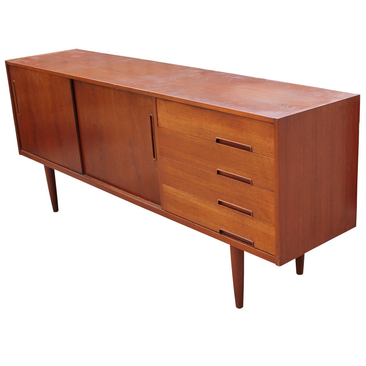 Beautiful clean lined teak credenza or sideboard. 1st of four drawers is slotted for service and has a sliding compartment. Two sliding doors open to a single shelf. Tapered legs.