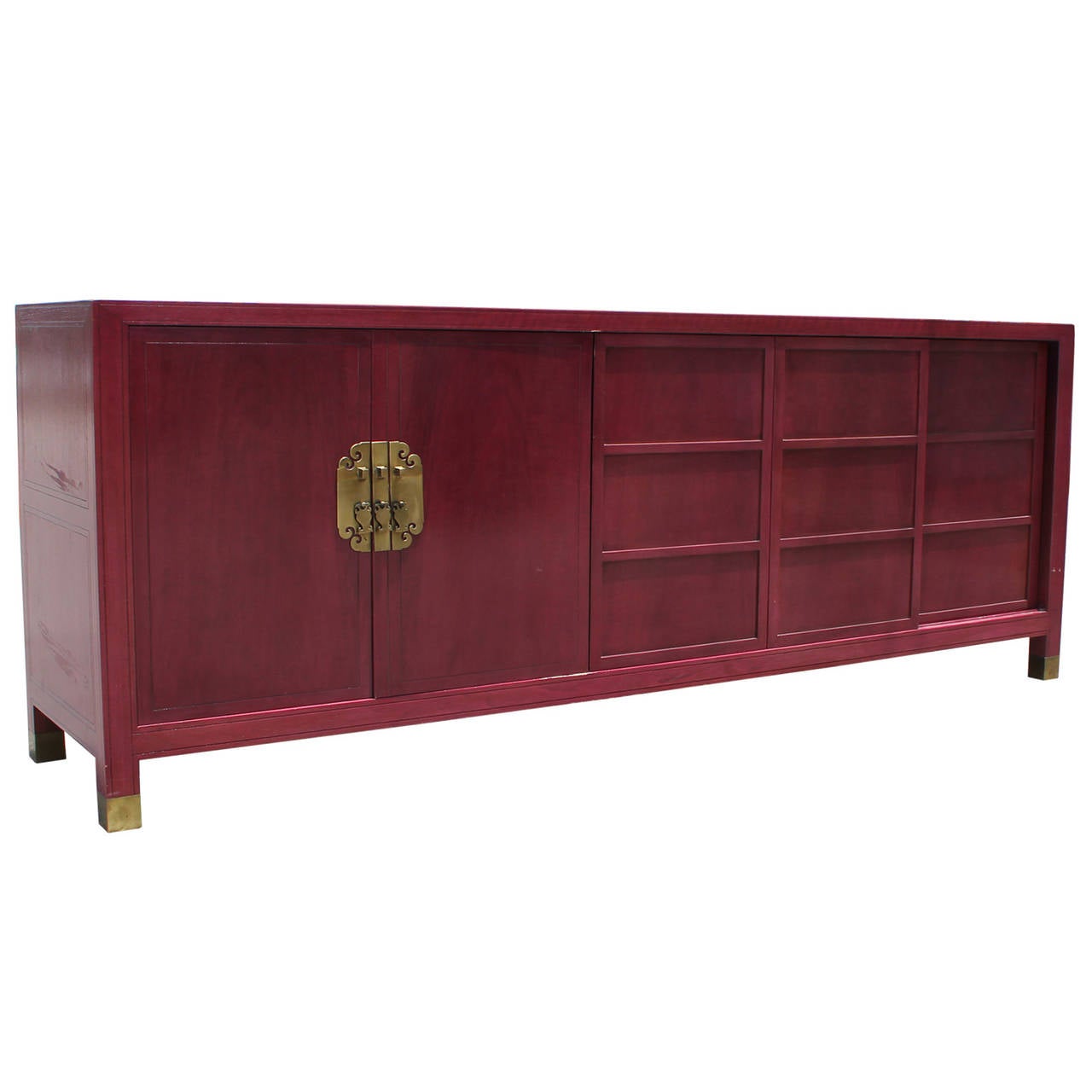 Gorgeous Baker Far East Collection raspberry stained sideboard. Hinged doors with large solid brass asian hardware open to reveal scalloped drawers. Three paneled sliding doors open to a single shelf. Top is adorned with a trio of engraved borders.