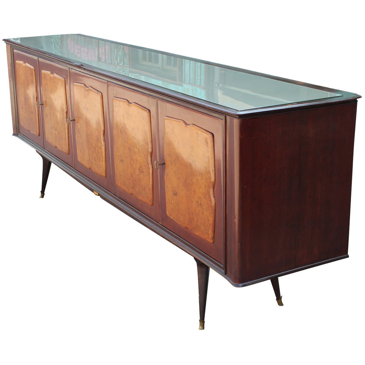Excellent sideboard or credenza made in Italy with burl wood front and a silver glass top. The sideboard sits atop a sculptural base with brass tipped feet. It was made in the mid-1950s. The sideboard reflects the style of Paolo Buffa. Each door has