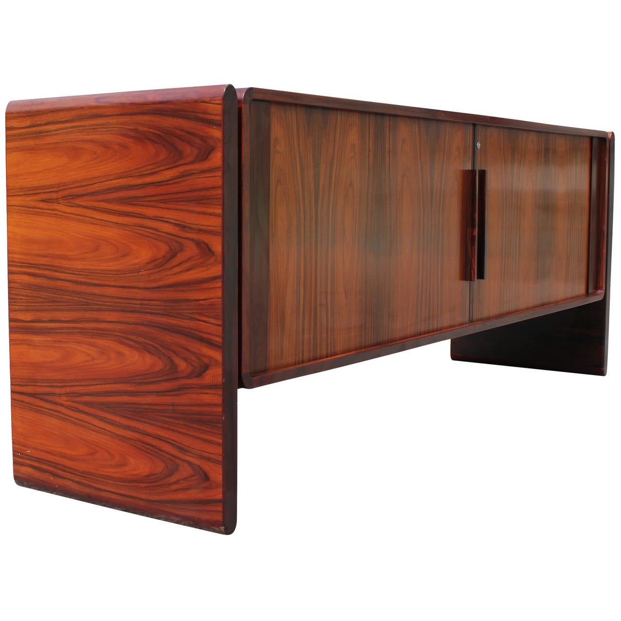Excellent tambour door rosewood sideboard by Dyrlund. Rosewood has an excellent grain. Left side has two shallow drawers and a pull out drawer for filing. Right side has one small drawer and a  large open space. Two legs float agains the case