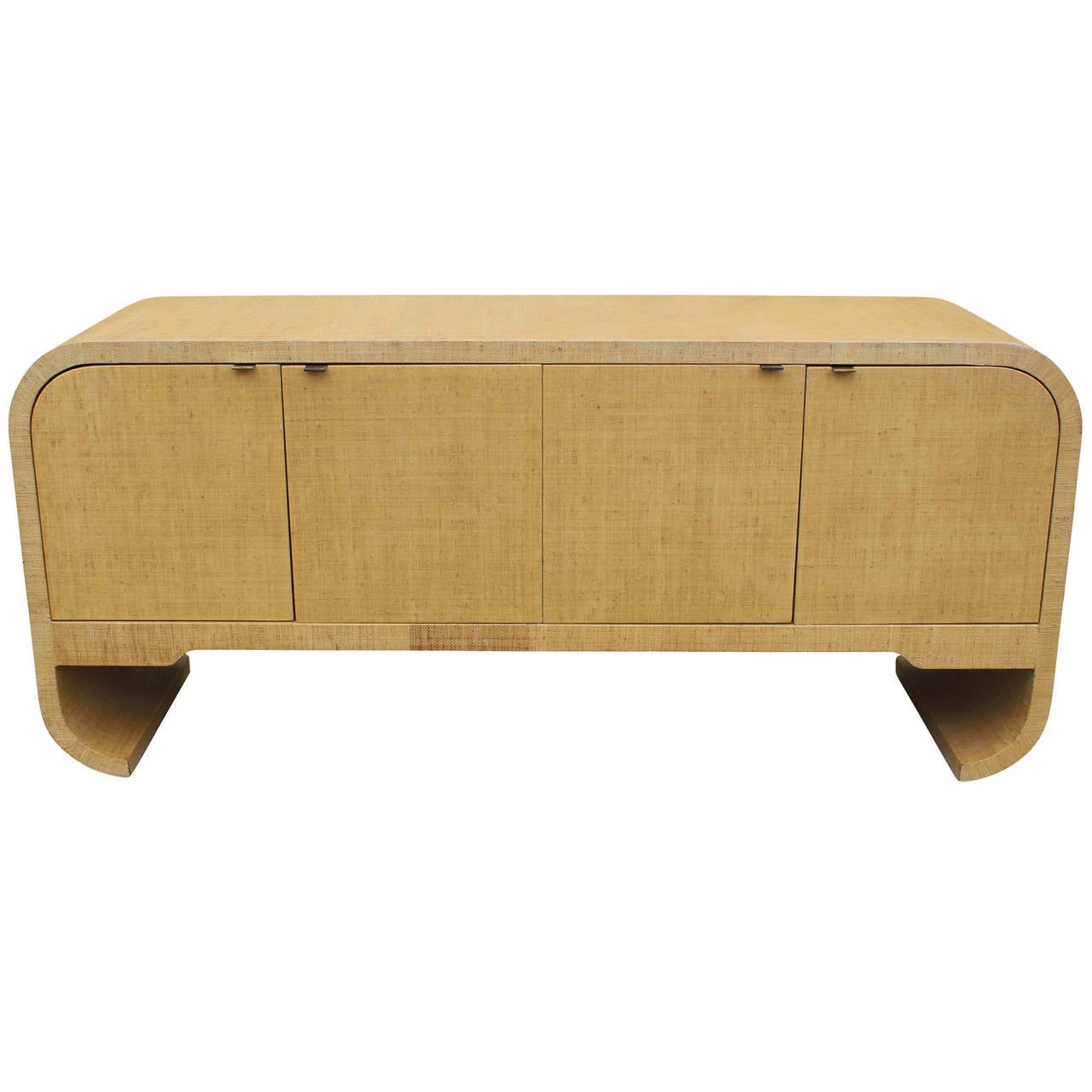 Fabulous sideboard in the style of Karl Springer. Sideboard is covered in a warm neutral seagrass or raffia topped with clear coat. Four doors are accented with minimalist brass pulls. Curved edges and dramatic scrolled legs make a statement. The