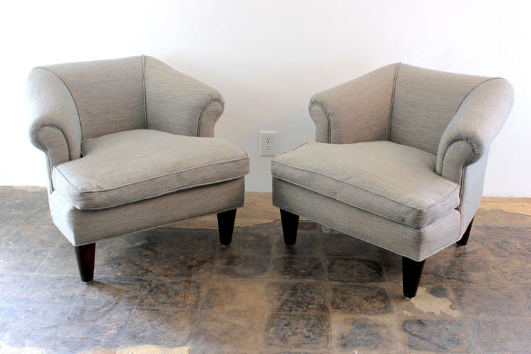 Rare pair of 1940s Dunbar club chairs designed by Edward Wormley. Original ottoman is also included. These chairs have been reupholstered in a woven cotton fabric. The chairs and ottoman sit on thick solid mahogany cone legs. The cushions are down