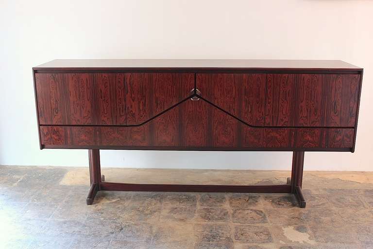 A stately unusual Brazilian rosewood envelope sideboard. Three doors in the center open envelope style to a bar. Beset by two cabinets with one felt lined service drawer. Excellent quality and construction by Mcintosh
