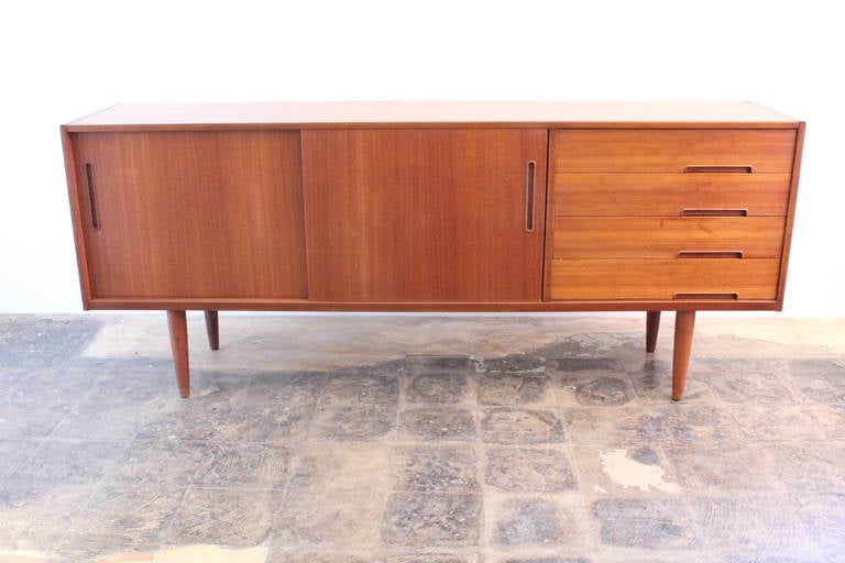 Clean teak Sideboard by Nils Jonsson for Troeds, made in Sweden. Beautiful sliding doors with four drawers on the right. Back has two small holes drilled to run wires for electronic equipment.