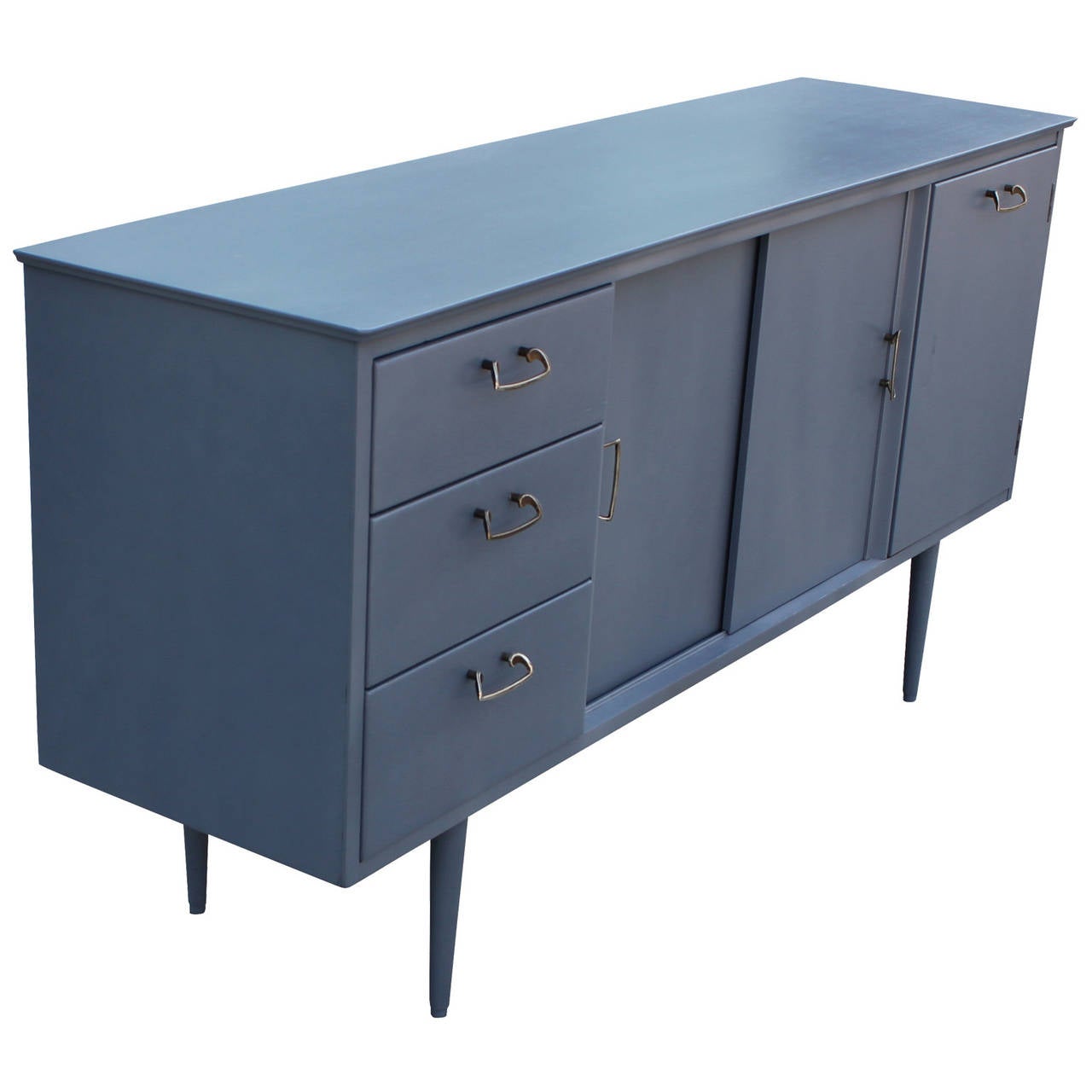 Light grey-blue sideboard with aged brass handles. Sideboard or Credenza is made out of teak. The piece has been stained a beautiful pale French Blue Grey. Chrome handles. The first of three drawers is slotted for service. Two sliding doors open to