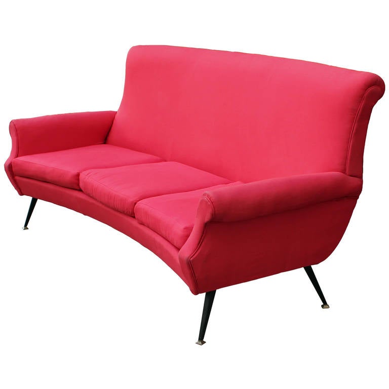 Sculptural curved Italian sofa in a red cotton fabric. Black metal legs with brass tips. Fabric has no rips or tears and is in good shape, circa 1950.