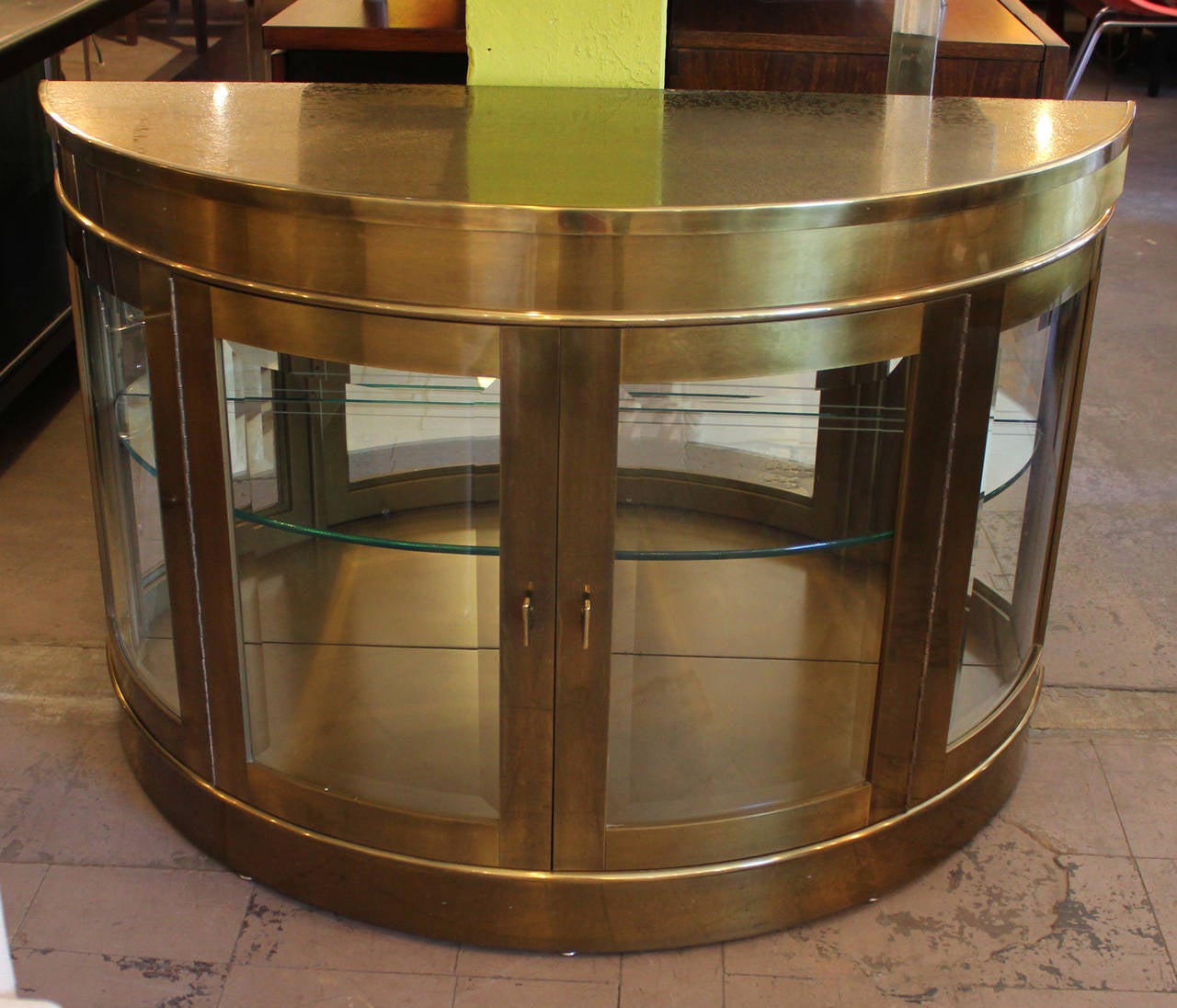 Excellent brass Mastercraft demilune display cabinet / vitrines. The cabinet glass fronts and shelves with an etched top. Item is is excellent vintage condition.