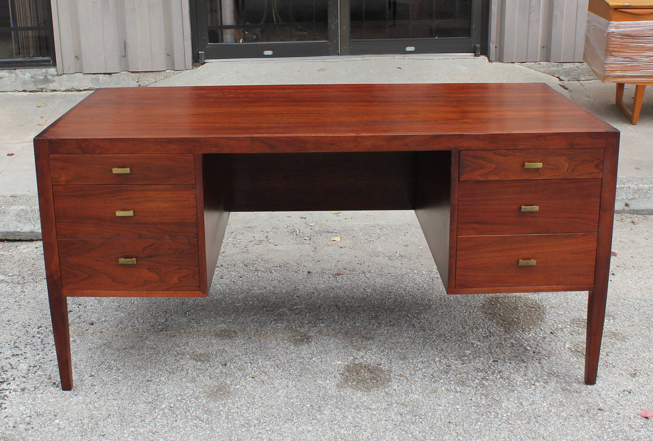 Fully restored walnut desk. Five drawers with brass pulls provide ample storage. Beautiful detailing on the top. IN the style of Baker Furniture.