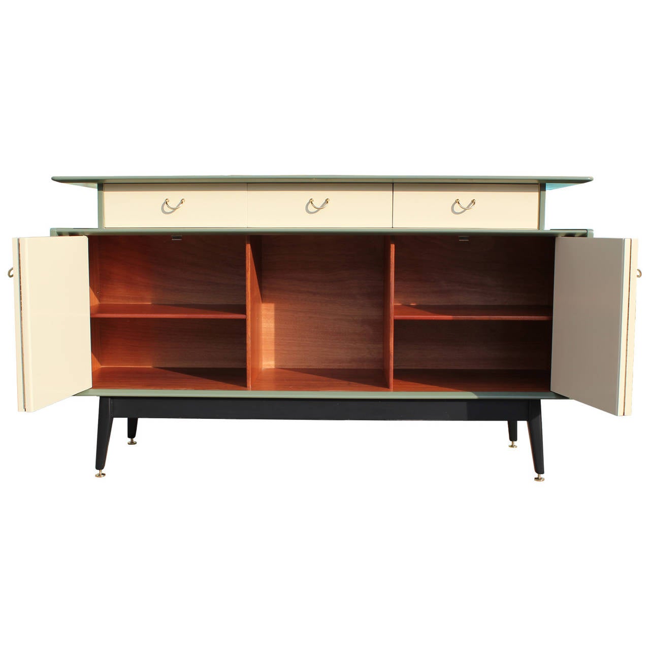 Stunning sideboard refinished in tone on tone green lacquer with brass levelers, piping, and handles. Three drawers line the top of the cabinet-center drawer is a slotted service drawer. Accordion doors open to reveal ample storage.