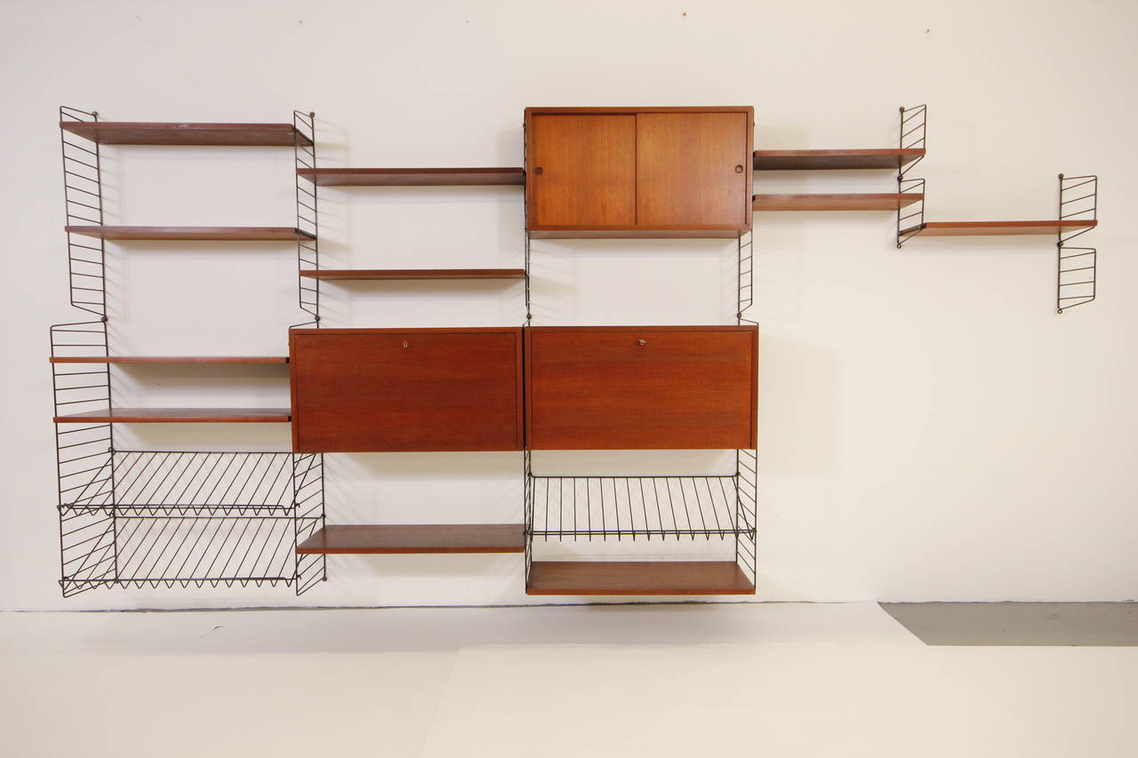 Absolutely gorgeous Swedish modular wall unit with amazing teak grain and brass detail. Original condition with fold out desk cabinet and bar cabinet. This unit is completely modular and very easy to configure to your needs.
